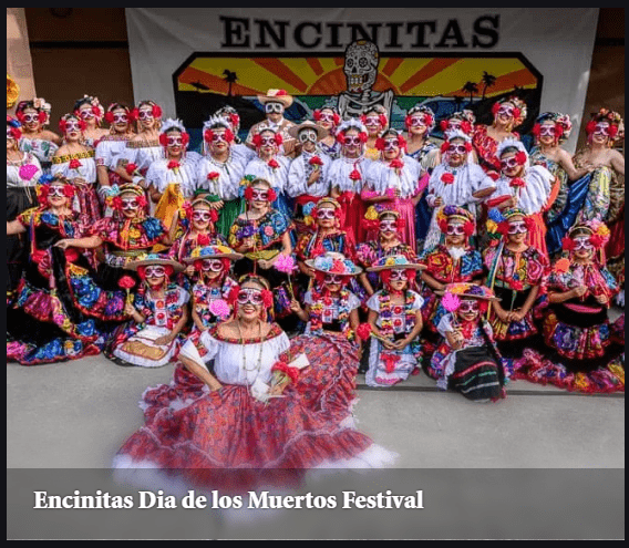 Encinitas Dia de los Muertos Festival features a vibrant group in colorful traditional attire, celebrating cultural heritage with elaborate costumes and decorations.