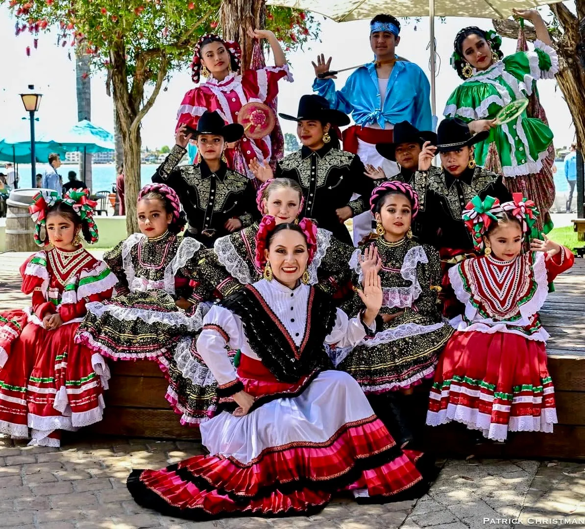 A group of dancers in traditional Mexican outfits poses outdoors, showcasing colorful costumes and vibrant cultural heritage.