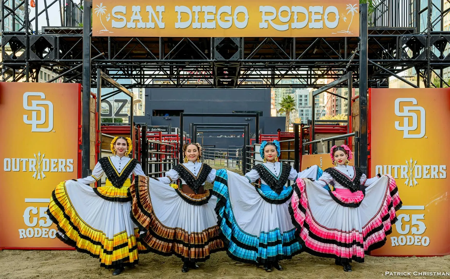 Women in traditional attire pose in front of the San Diego Rodeo entrance, showcasing vibrant dresses and cultural celebration.